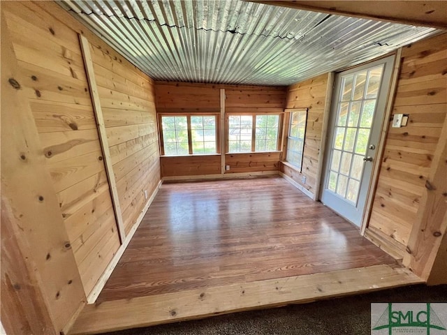 interior space featuring wood-type flooring, wooden ceiling, and wooden walls