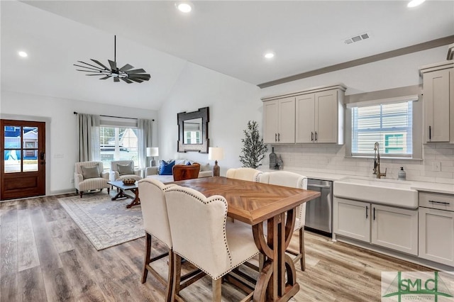 dining space with ceiling fan, sink, lofted ceiling, and light wood-type flooring