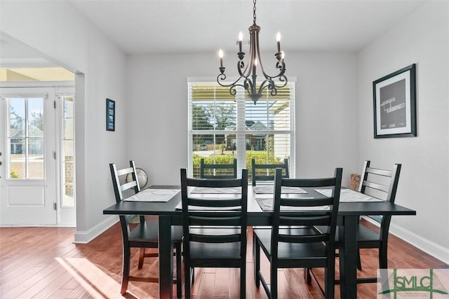 dining area with hardwood / wood-style floors, plenty of natural light, and an inviting chandelier