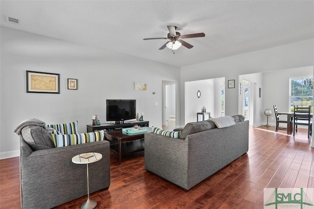 living room with ceiling fan, dark hardwood / wood-style floors, and a textured ceiling