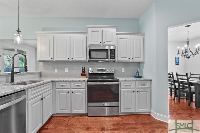 kitchen featuring white cabinets, sink, decorative backsplash, appliances with stainless steel finishes, and wood-type flooring