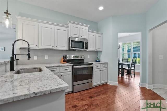 kitchen featuring white cabinets, sink, decorative backsplash, appliances with stainless steel finishes, and decorative light fixtures