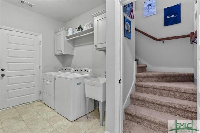 washroom with separate washer and dryer, light tile patterned floors, and cabinets