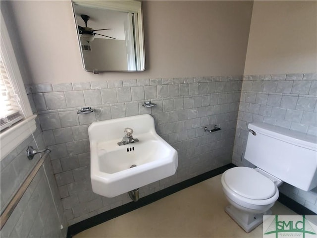 bathroom featuring toilet, tile walls, and sink