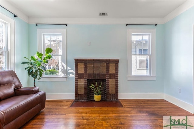 living room featuring a fireplace, dark hardwood / wood-style flooring, plenty of natural light, and ornamental molding