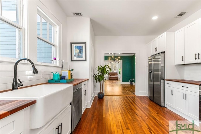 kitchen featuring sink, wood counters, dark hardwood / wood-style flooring, white cabinets, and appliances with stainless steel finishes