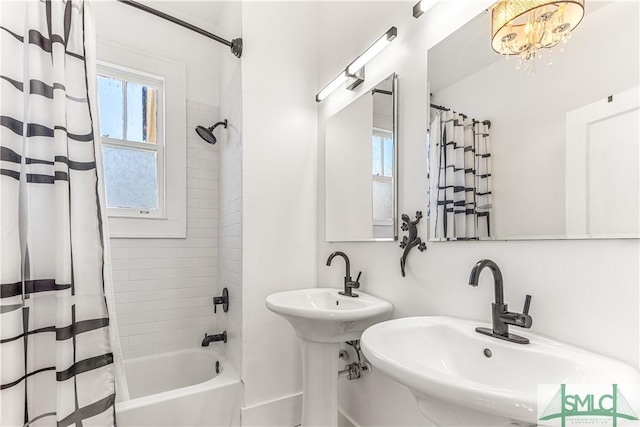 bathroom with a notable chandelier, dual sinks, shower / bathtub combination with curtain, and a wealth of natural light