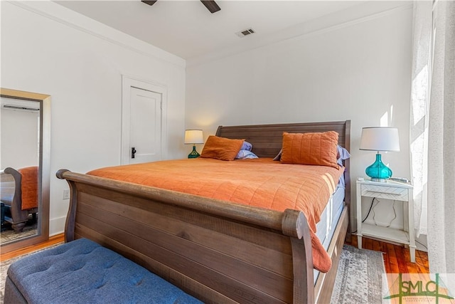 bedroom with ceiling fan, crown molding, and dark wood-type flooring