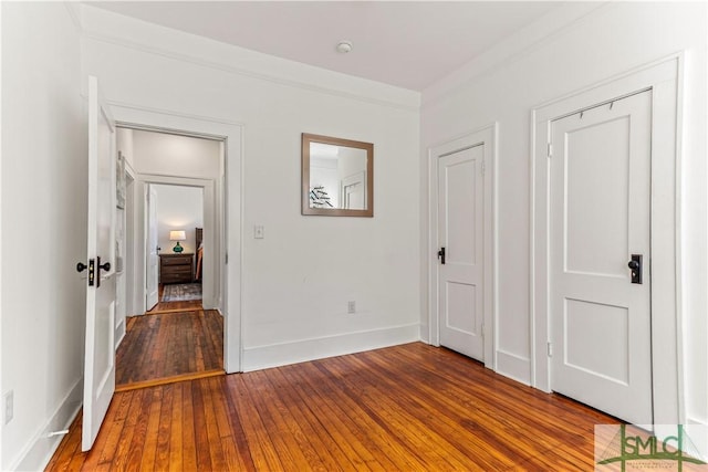 unfurnished bedroom featuring wood-type flooring and crown molding