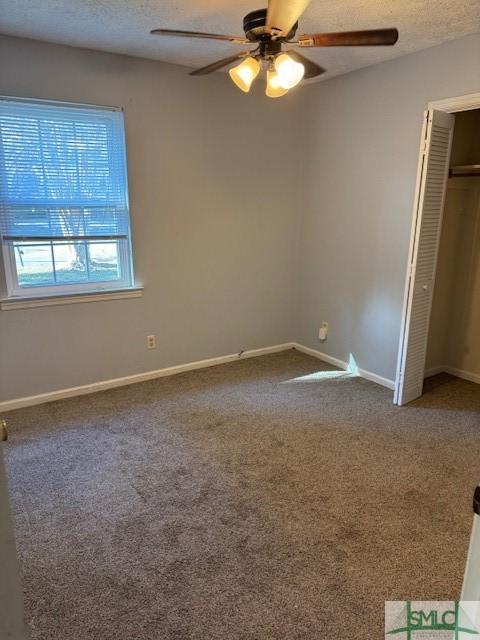 unfurnished bedroom featuring ceiling fan, a closet, carpet floors, and a textured ceiling