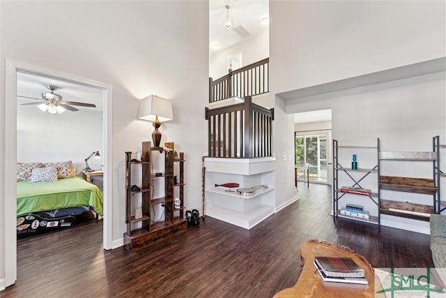 interior space with ceiling fan, wood-type flooring, and a high ceiling