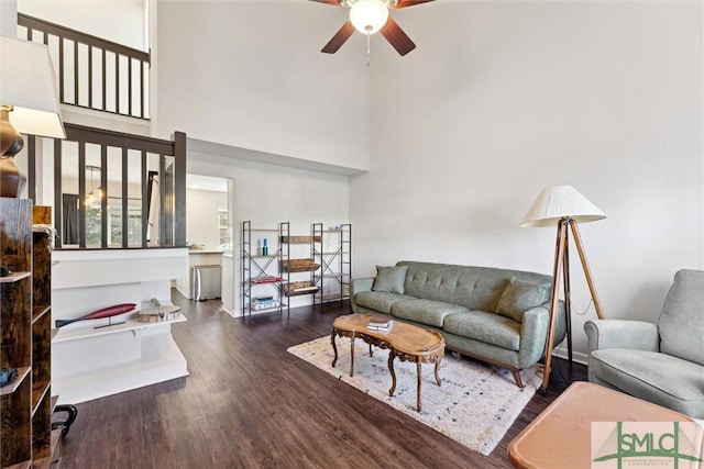 living room featuring ceiling fan, dark hardwood / wood-style flooring, and a high ceiling