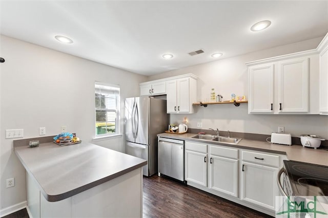 kitchen with sink, dark hardwood / wood-style floors, white cabinetry, kitchen peninsula, and stainless steel appliances