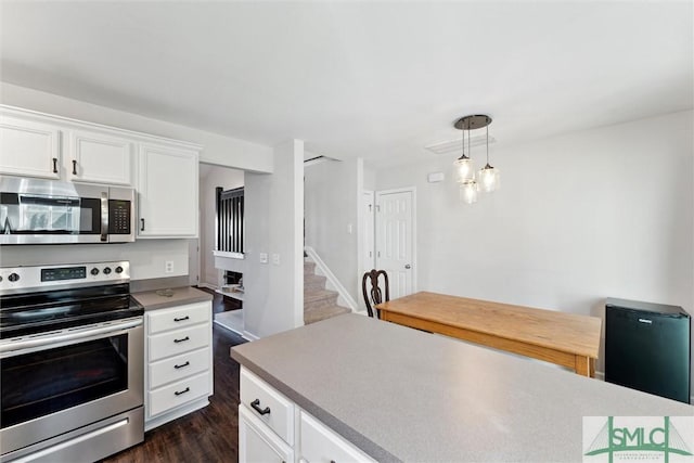 kitchen with dark hardwood / wood-style flooring, white cabinets, decorative light fixtures, and appliances with stainless steel finishes