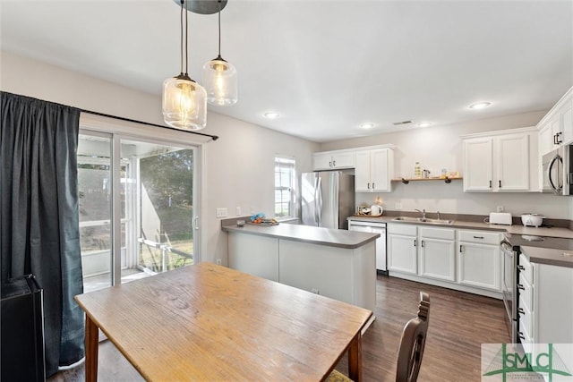 kitchen with sink, white cabinets, hanging light fixtures, and appliances with stainless steel finishes