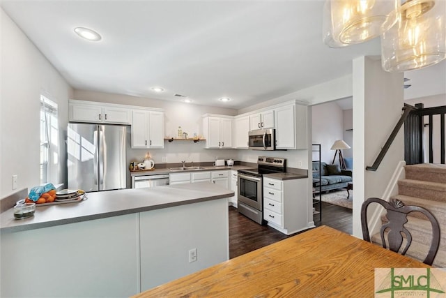 kitchen with stainless steel appliances, dark wood-type flooring, sink, white cabinetry, and hanging light fixtures