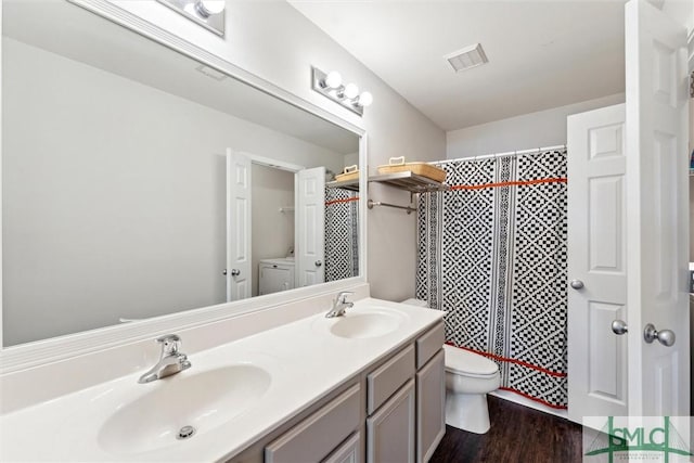 bathroom featuring hardwood / wood-style flooring, vanity, toilet, and washer / dryer