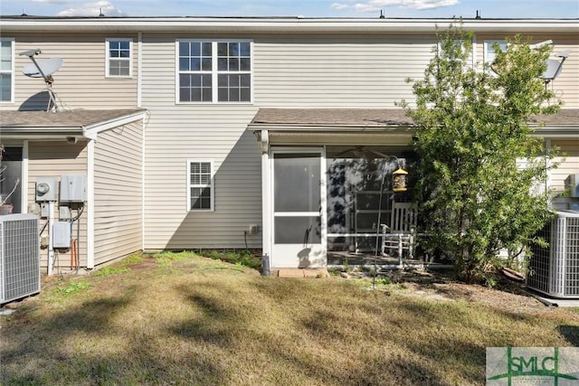 rear view of property featuring a sunroom, central AC, and a lawn