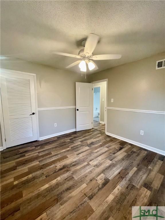 unfurnished bedroom featuring ceiling fan, dark wood-type flooring, and a textured ceiling