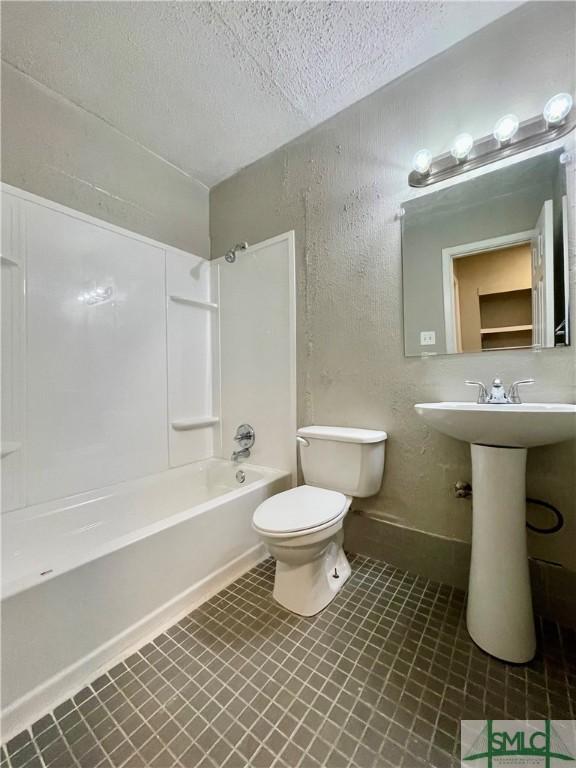 full bathroom featuring sink, toilet, washtub / shower combination, and a textured ceiling