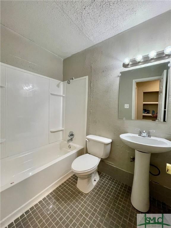 bathroom featuring toilet, a textured ceiling, and bathing tub / shower combination