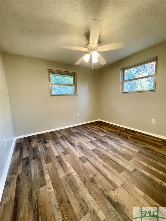 empty room featuring ceiling fan, dark hardwood / wood-style flooring, and a textured ceiling