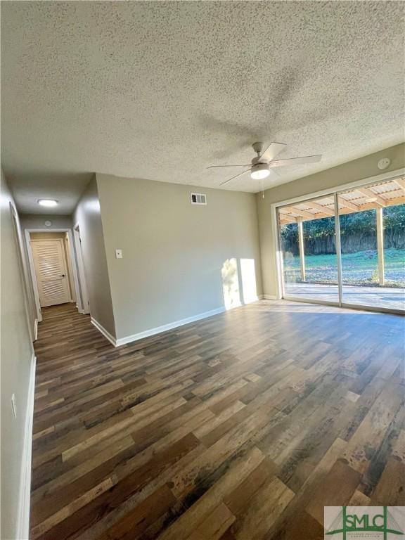 unfurnished room featuring ceiling fan, dark wood-type flooring, and a textured ceiling