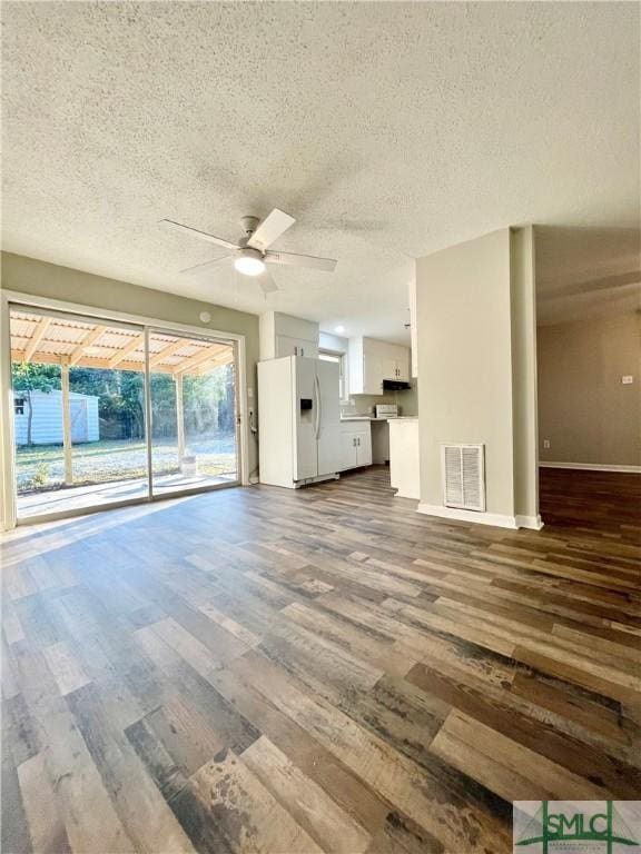 unfurnished living room featuring a textured ceiling, ceiling fan, and dark wood-type flooring