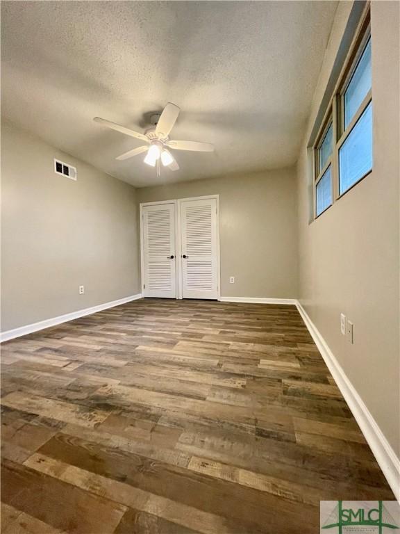 unfurnished bedroom with ceiling fan, wood-type flooring, and a textured ceiling