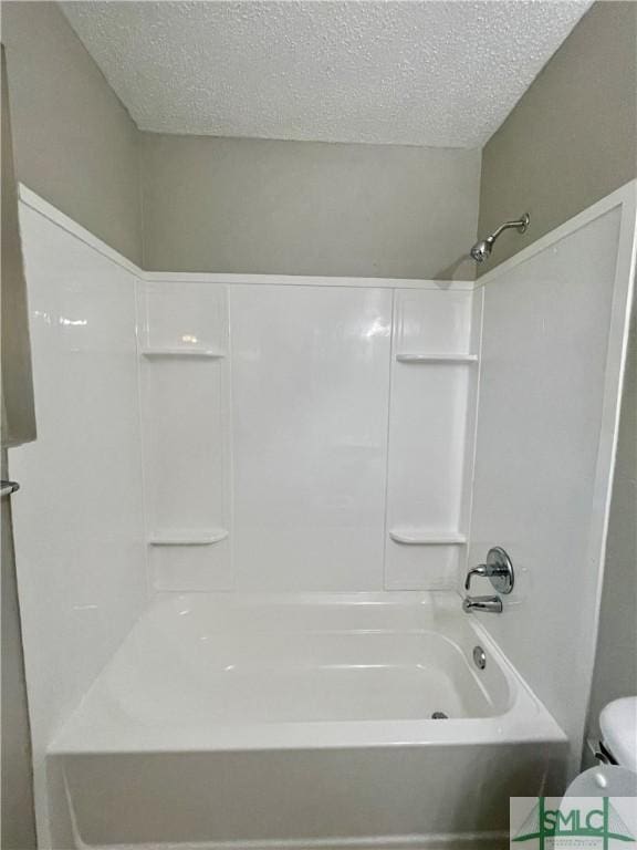 bathroom featuring toilet, a textured ceiling, and bathing tub / shower combination