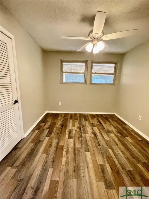 unfurnished room featuring a textured ceiling, ceiling fan, and dark wood-type flooring