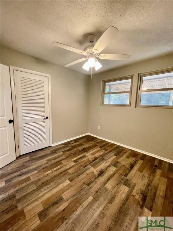 unfurnished bedroom with a textured ceiling, a closet, ceiling fan, and dark hardwood / wood-style floors