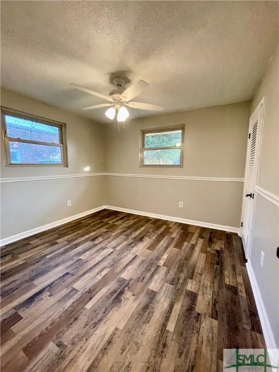 unfurnished room with a textured ceiling, dark hardwood / wood-style flooring, and ceiling fan