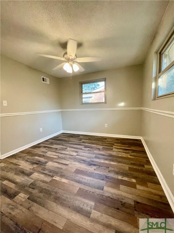 spare room with a textured ceiling, ceiling fan, and dark hardwood / wood-style floors