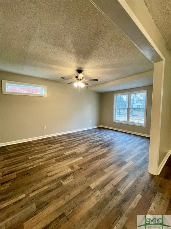 empty room featuring a textured ceiling, dark hardwood / wood-style flooring, and ceiling fan