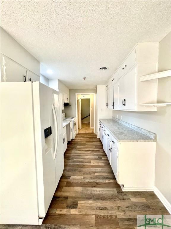 kitchen with white cabinets, a textured ceiling, white appliances, and dark hardwood / wood-style flooring