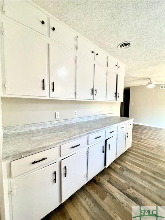 kitchen with ceiling fan, dark hardwood / wood-style flooring, white cabinetry, and a textured ceiling