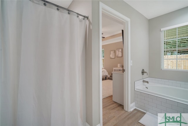 bathroom with tiled tub and hardwood / wood-style flooring