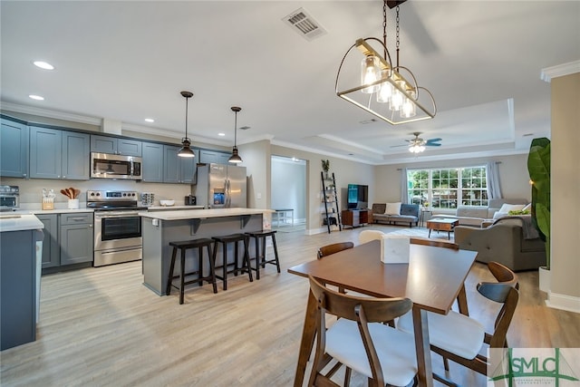 dining room featuring ceiling fan with notable chandelier, light hardwood / wood-style floors, a raised ceiling, and ornamental molding