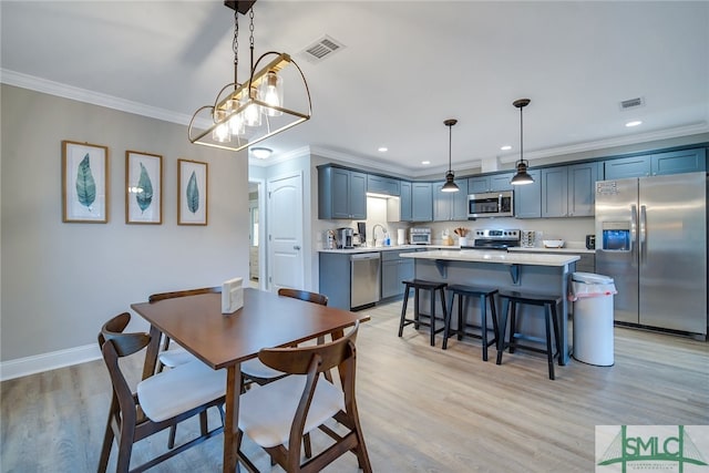 dining area featuring light hardwood / wood-style flooring, crown molding, and sink