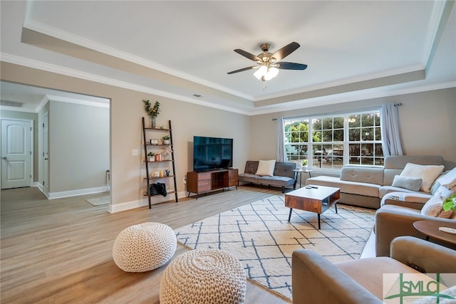 living room with a raised ceiling, ceiling fan, crown molding, and light hardwood / wood-style floors