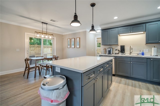 kitchen featuring sink, hanging light fixtures, crown molding, a kitchen island, and light wood-type flooring