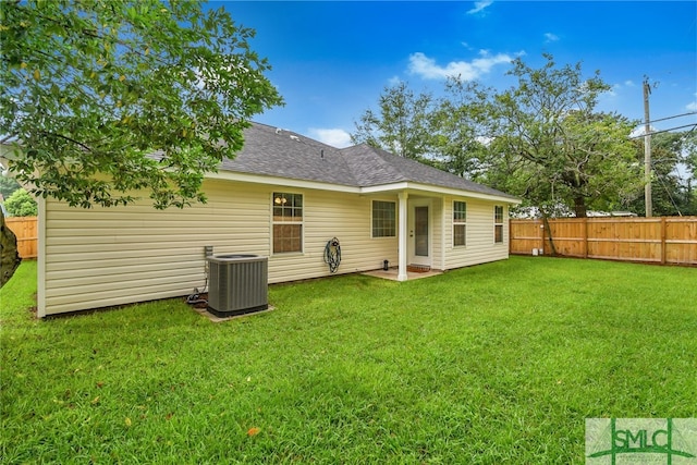 rear view of house featuring cooling unit and a yard