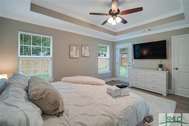 bedroom featuring wood-type flooring, a tray ceiling, ceiling fan, and crown molding