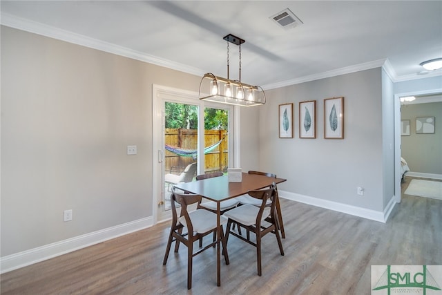 dining space with crown molding, an inviting chandelier, and hardwood / wood-style flooring