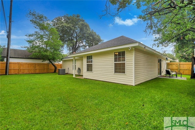 rear view of property featuring a lawn and central air condition unit