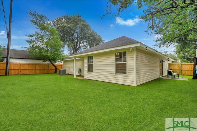 rear view of house with central AC and a lawn