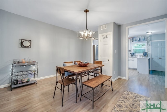 dining space featuring light hardwood / wood-style flooring and an inviting chandelier