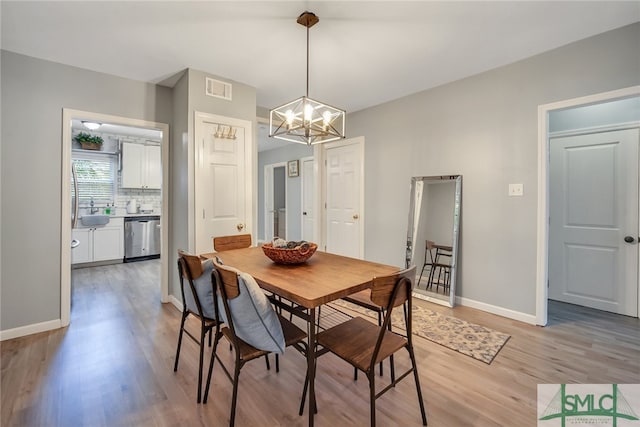 dining room featuring a notable chandelier, sink, and light hardwood / wood-style flooring