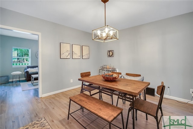 dining area with light hardwood / wood-style floors and a chandelier